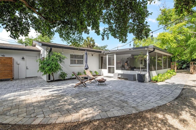 rear view of house with a fire pit, a patio area, and a sunroom