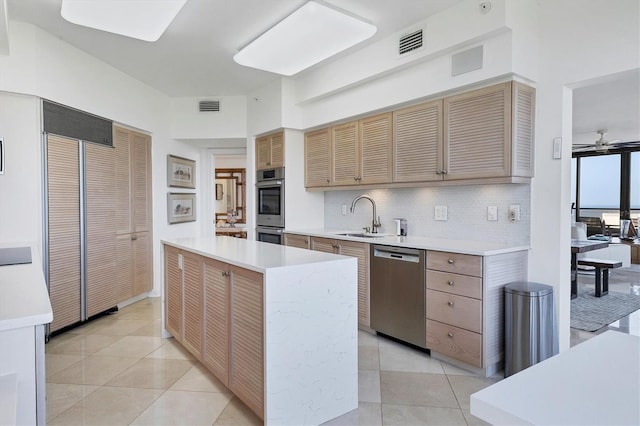 kitchen with ceiling fan, a kitchen island, sink, and stainless steel appliances