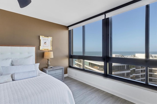 bedroom featuring multiple windows, a water view, and hardwood / wood-style flooring