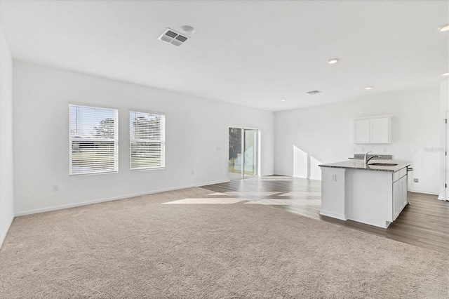 unfurnished living room with sink and carpet floors