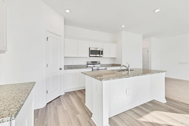 kitchen with a kitchen island with sink, sink, white cabinets, and appliances with stainless steel finishes