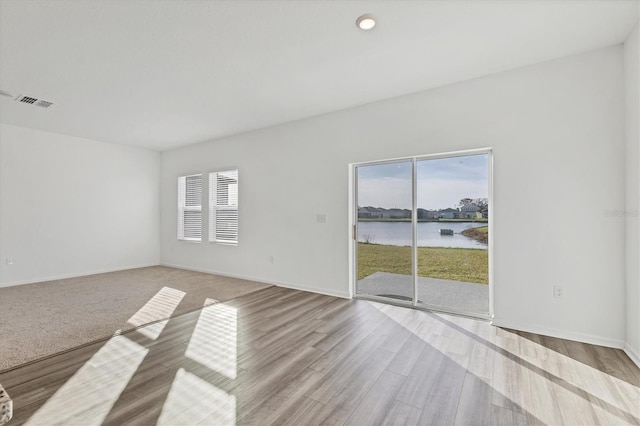 empty room with plenty of natural light, a water view, and light hardwood / wood-style flooring