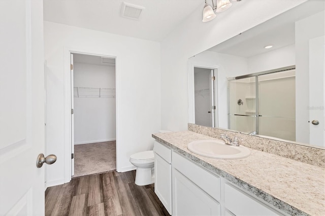 bathroom featuring hardwood / wood-style floors, vanity, toilet, and a shower with door