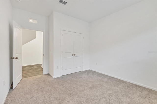 unfurnished bedroom featuring light carpet and a closet