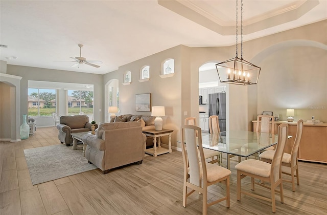 dining room featuring ceiling fan with notable chandelier and a tray ceiling