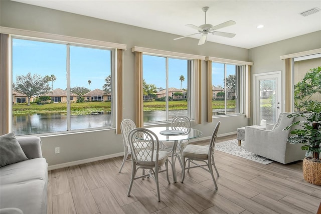 sunroom / solarium with a water view and ceiling fan