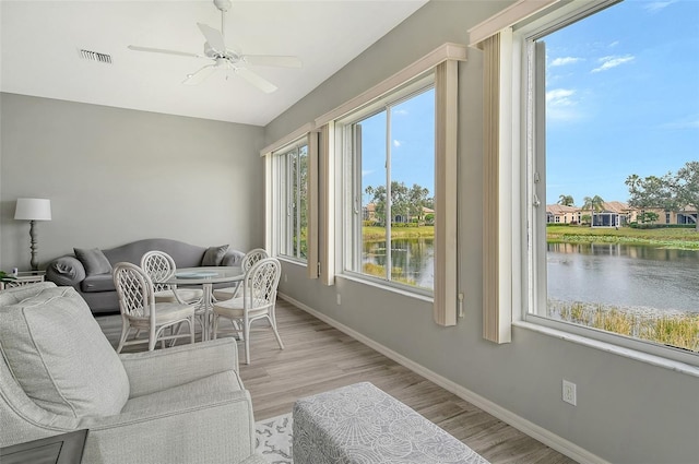 sunroom / solarium featuring a water view and ceiling fan