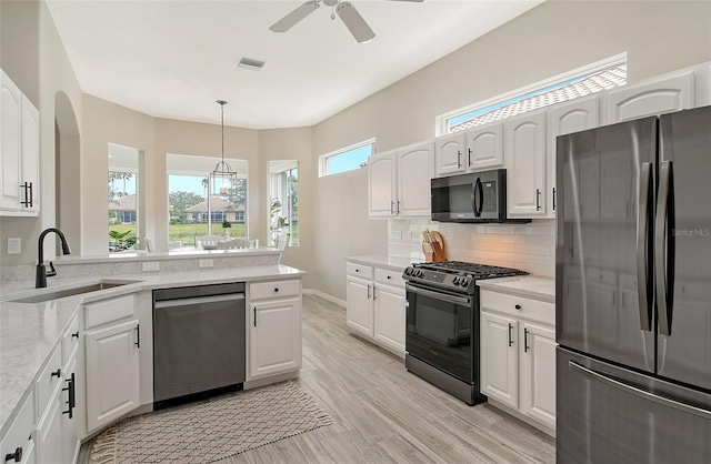 kitchen with light stone countertops, white cabinetry, sink, decorative light fixtures, and black appliances