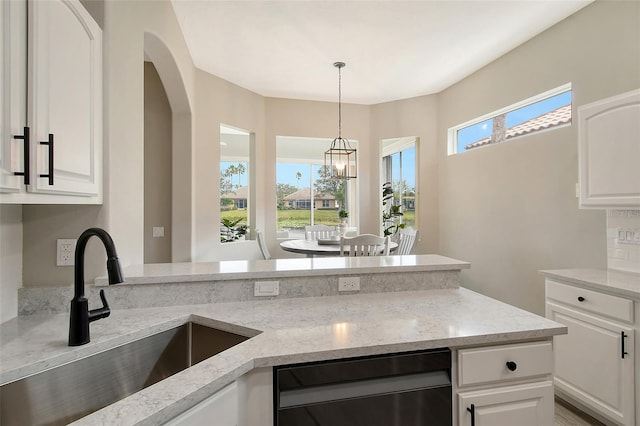 kitchen featuring light stone countertops, sink, white cabinets, and pendant lighting