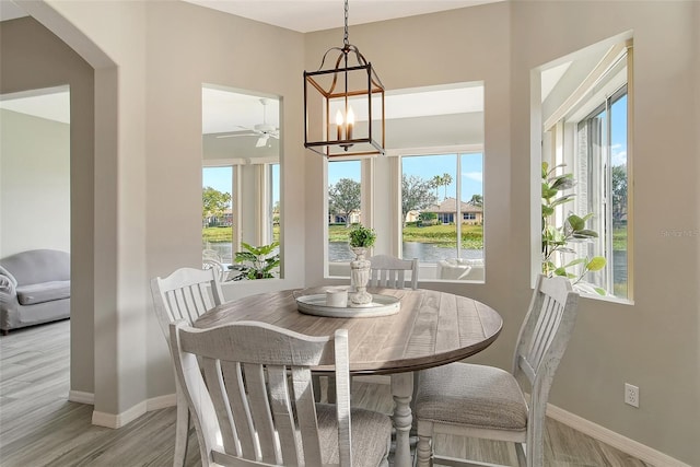 dining room with a water view, a notable chandelier, and light wood-type flooring