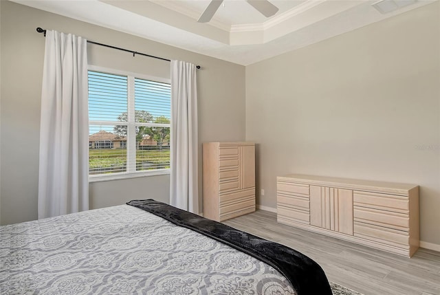 bedroom featuring a raised ceiling, ceiling fan, crown molding, and light wood-type flooring