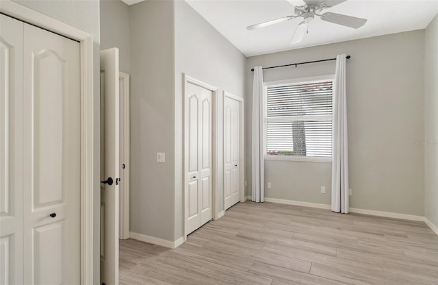 unfurnished bedroom with multiple closets, ceiling fan, and light hardwood / wood-style floors