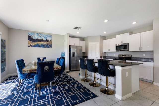 kitchen with white cabinets, a kitchen breakfast bar, an island with sink, and appliances with stainless steel finishes