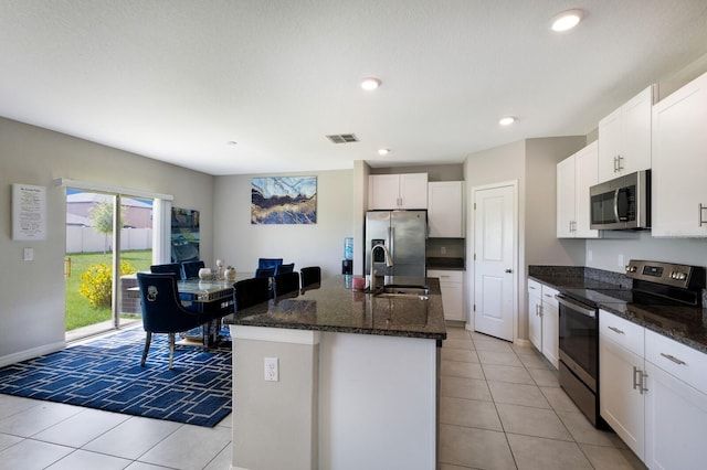 kitchen with white cabinetry, sink, a kitchen island with sink, light tile patterned floors, and appliances with stainless steel finishes