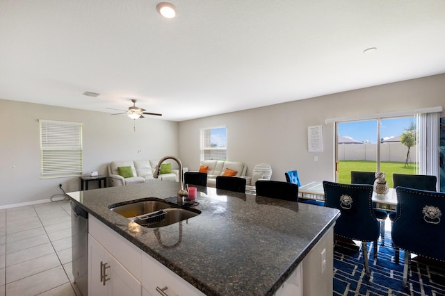 kitchen with sink, dark stone countertops, dishwasher, white cabinetry, and an island with sink