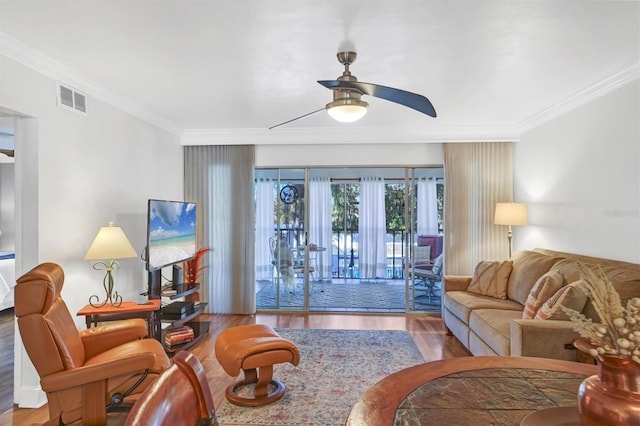 living area with ornamental molding, visible vents, ceiling fan, and wood finished floors