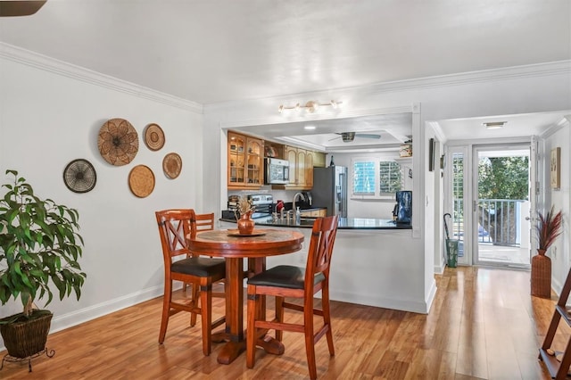 dining room featuring ceiling fan, sink, light wood-type flooring, and crown molding