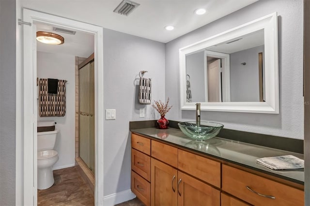 bathroom featuring vanity, toilet, and a shower with shower door