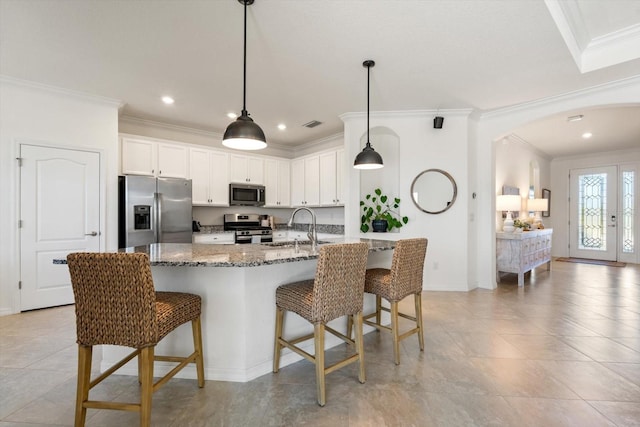 kitchen with dark stone counters, white cabinets, sink, appliances with stainless steel finishes, and a breakfast bar area