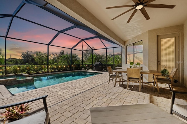 pool at dusk featuring an in ground hot tub, a patio, glass enclosure, and ceiling fan