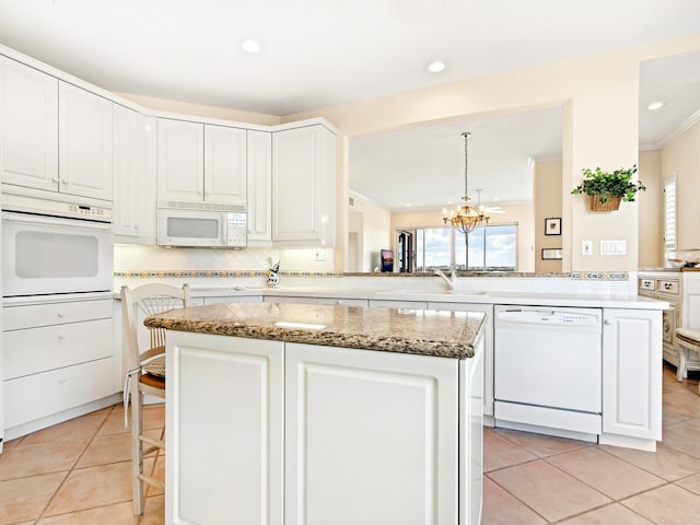 kitchen featuring sink, hanging light fixtures, kitchen peninsula, white appliances, and a kitchen island