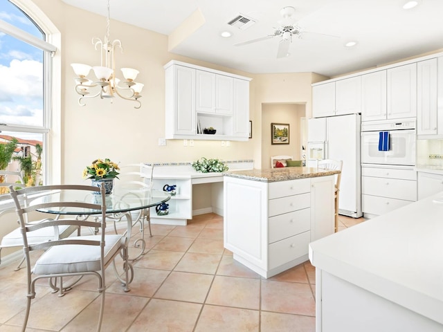 kitchen with a center island, white appliances, white cabinets, hanging light fixtures, and light tile patterned flooring