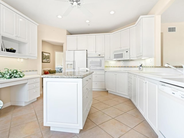 kitchen with white appliances, a center island, white cabinetry, and sink