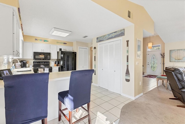 kitchen featuring kitchen peninsula, sink, black appliances, white cabinets, and light tile patterned flooring