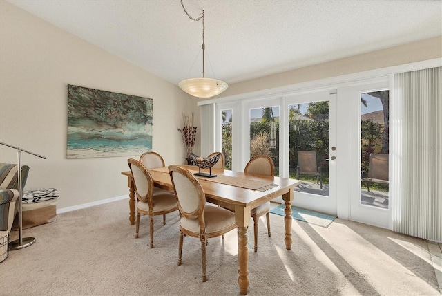 carpeted dining area featuring vaulted ceiling