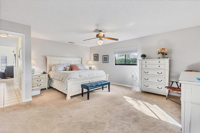 bedroom with ceiling fan, light colored carpet, and a textured ceiling