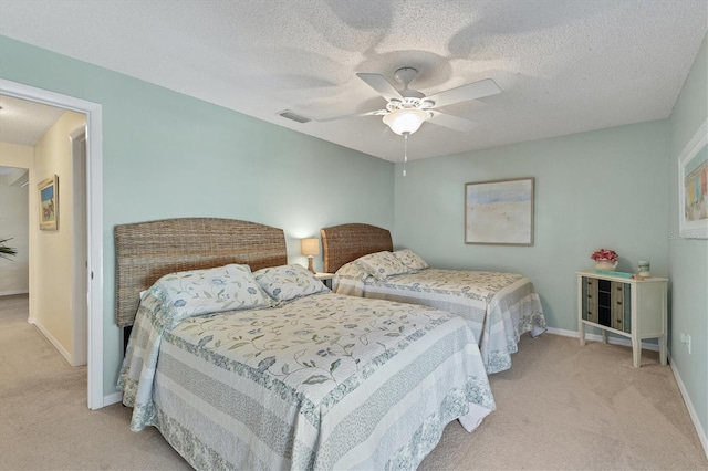 bedroom with ceiling fan, light colored carpet, and a textured ceiling