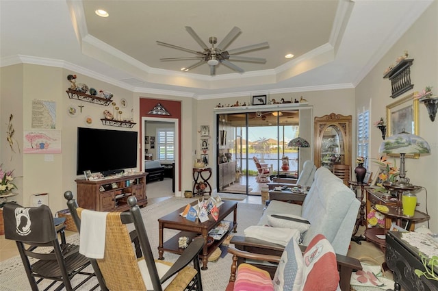 living room featuring a raised ceiling, ceiling fan, and ornamental molding