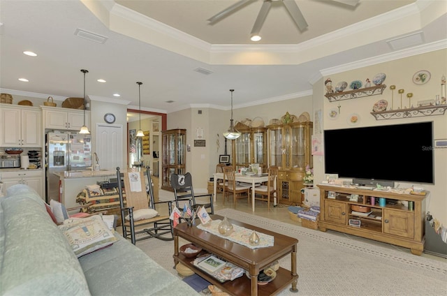 living room featuring a tray ceiling, ceiling fan, light tile patterned flooring, and ornamental molding