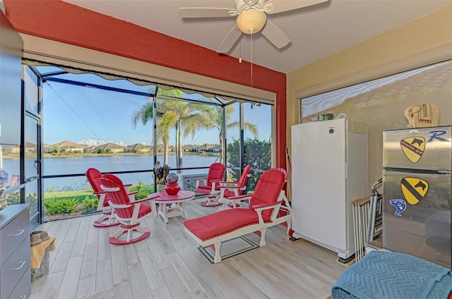 sunroom / solarium featuring ceiling fan and a water view