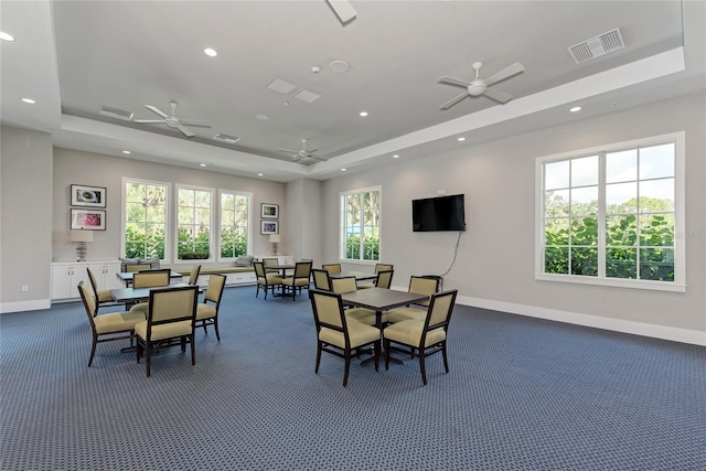 dining space featuring a tray ceiling, ceiling fan, and dark carpet