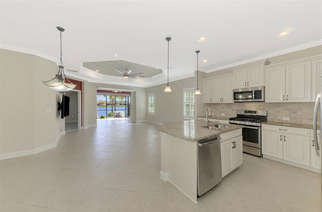 kitchen featuring an island with sink, open floor plan, light stone countertops, stainless steel appliances, and a sink