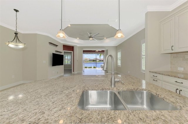 kitchen with open floor plan, white cabinets, a sink, and a raised ceiling