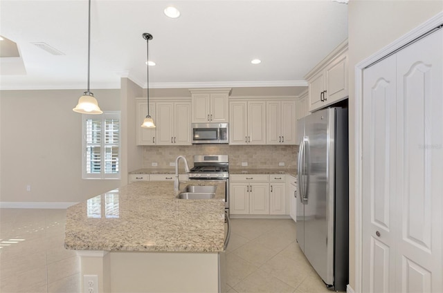 kitchen with hanging light fixtures, light stone countertops, a kitchen island with sink, stainless steel appliances, and light tile patterned flooring