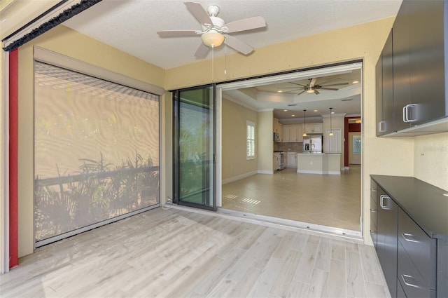 empty room featuring ceiling fan, recessed lighting, baseboards, light wood-type flooring, and a tray ceiling