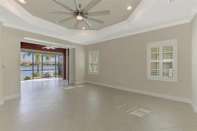 unfurnished room featuring a water view, light tile patterned floors, a raised ceiling, and crown molding