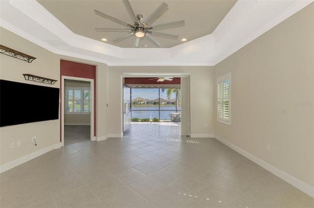 spare room with baseboards, a tray ceiling, and ornamental molding