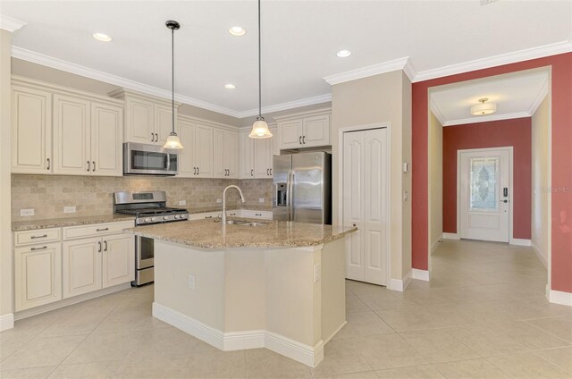 kitchen featuring light stone counters, decorative light fixtures, stainless steel appliances, a sink, and an island with sink