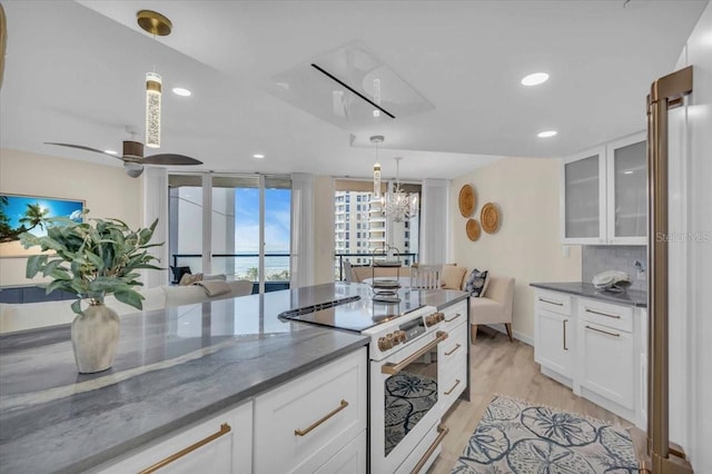 kitchen featuring white cabinets, decorative light fixtures, dark stone countertops, and electric stove