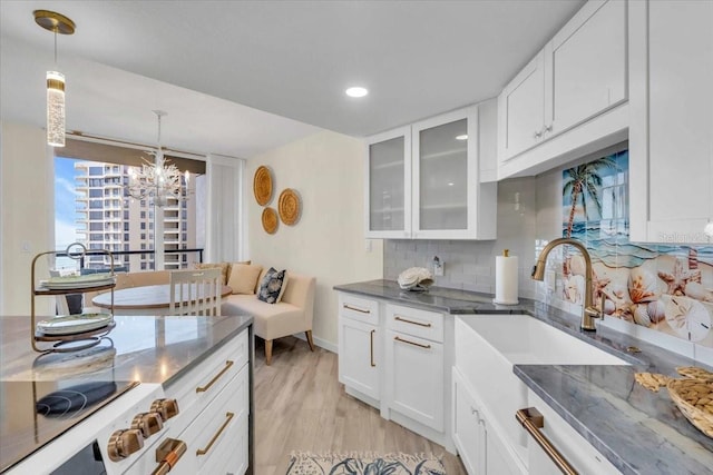 kitchen featuring white cabinetry, sink, tasteful backsplash, pendant lighting, and light hardwood / wood-style floors