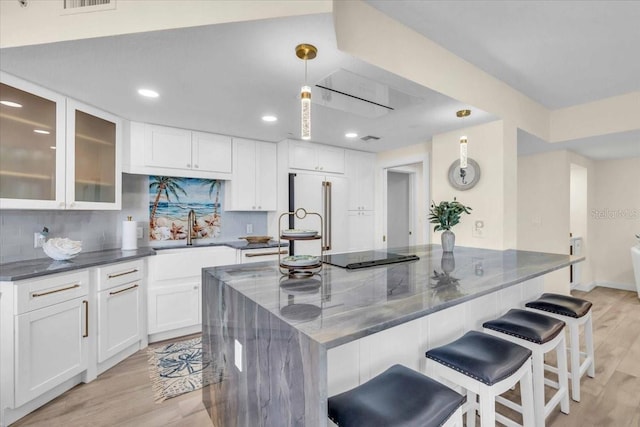 kitchen with tasteful backsplash, high quality fridge, a breakfast bar area, hanging light fixtures, and a large island