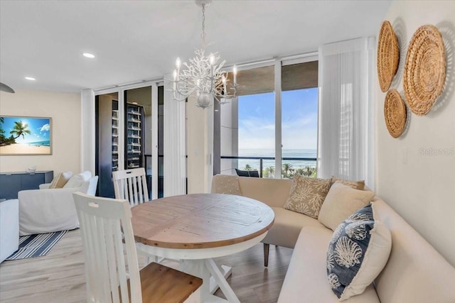 dining space with light hardwood / wood-style flooring, expansive windows, and an inviting chandelier