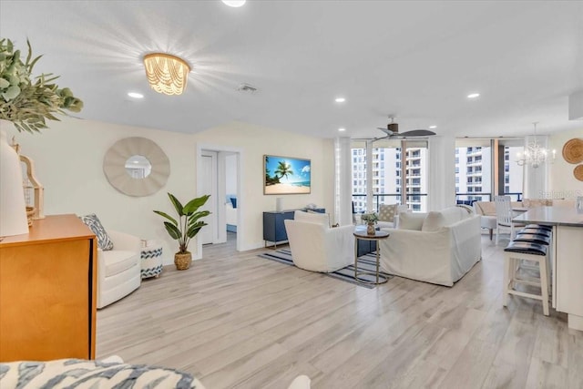 living room featuring ceiling fan with notable chandelier and light hardwood / wood-style floors