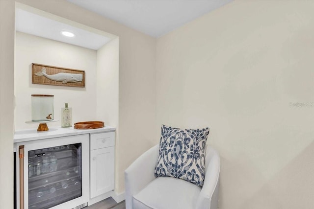 bar with white cabinets, beverage cooler, and hardwood / wood-style flooring