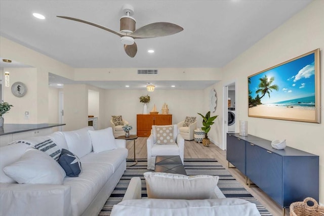 living room with washer / dryer, ceiling fan, and light wood-type flooring