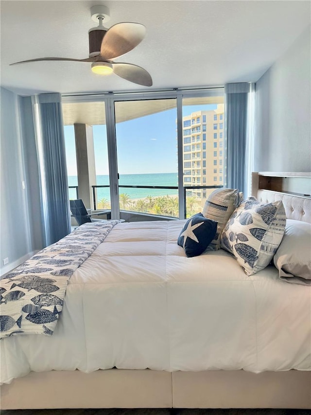 bedroom featuring multiple windows, ceiling fan, and a water view